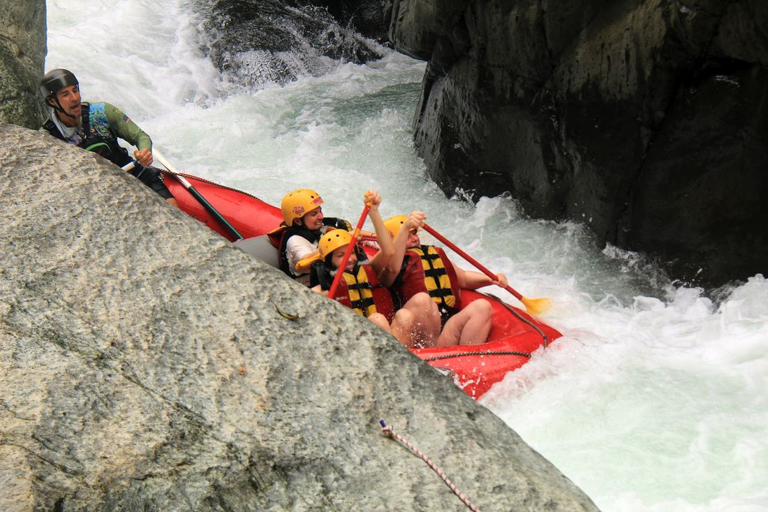 A guide steering a raft past a huge boulder on El Chorro