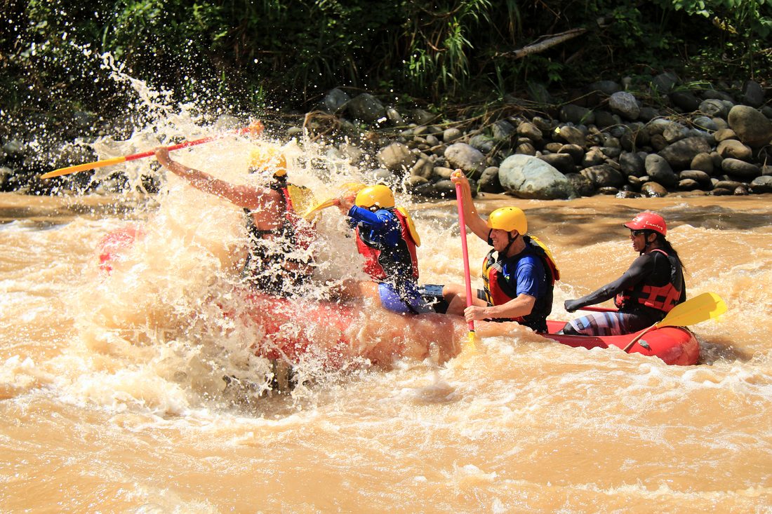 A raft pushing through a wave of brown water on the Savegre