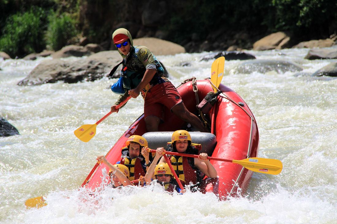 Guide steering a family raft on the Savegre river