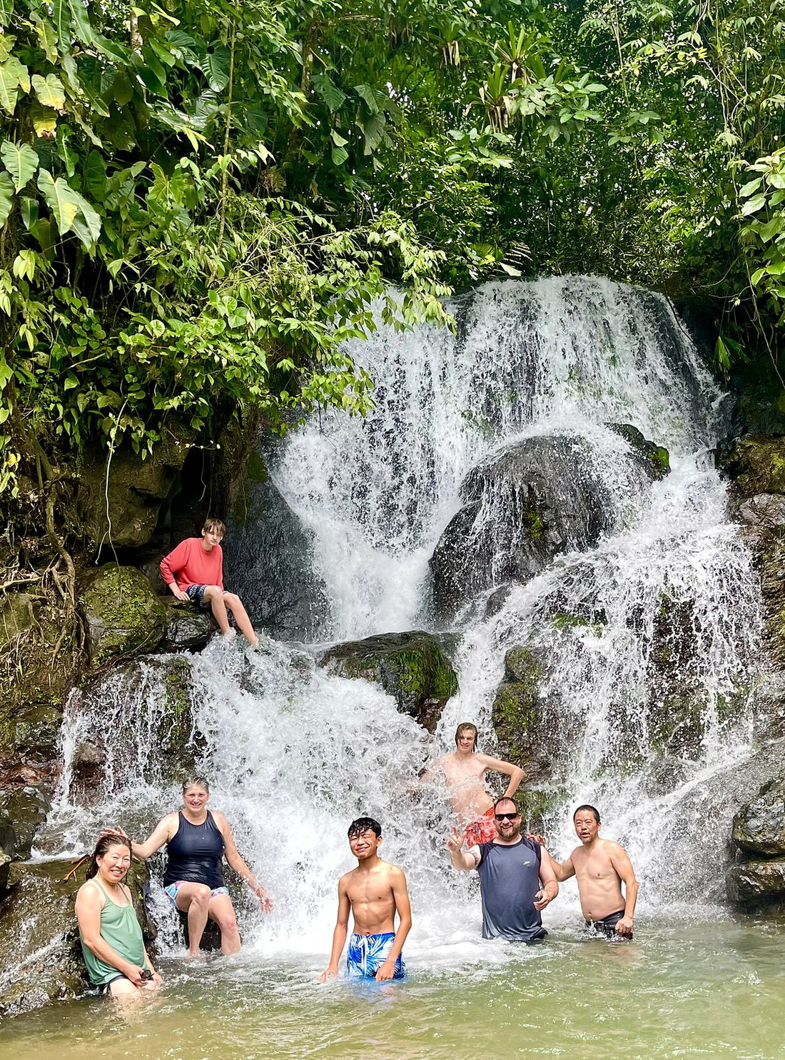 Guests standing in the pool of a rainforest waterfall near Quepos