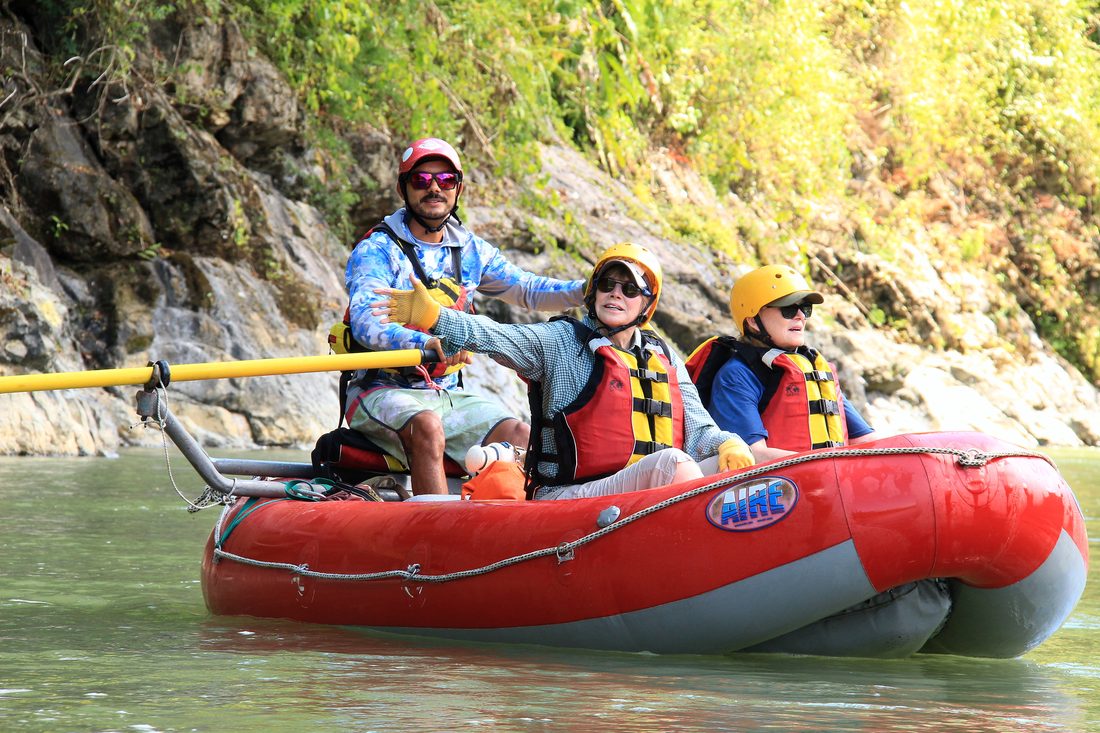 A guide rowing a raft of relaxed guests on the Savegre
