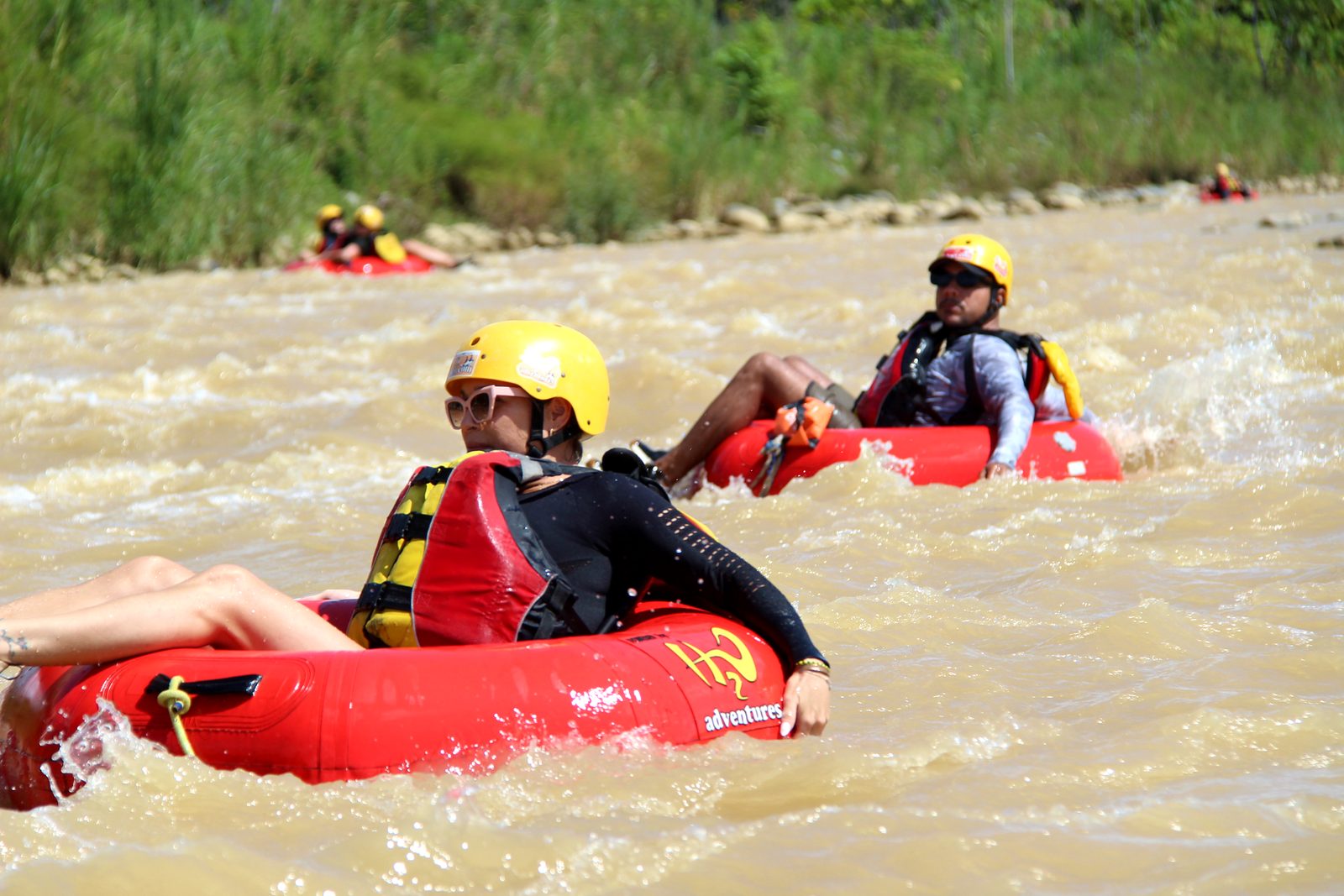 Two guests in red tubes ride the current on the Naranjo, more tubers behind