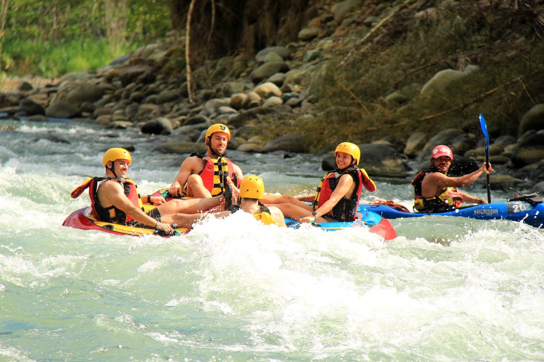 A line of tubers floating down a rapid with their guide
