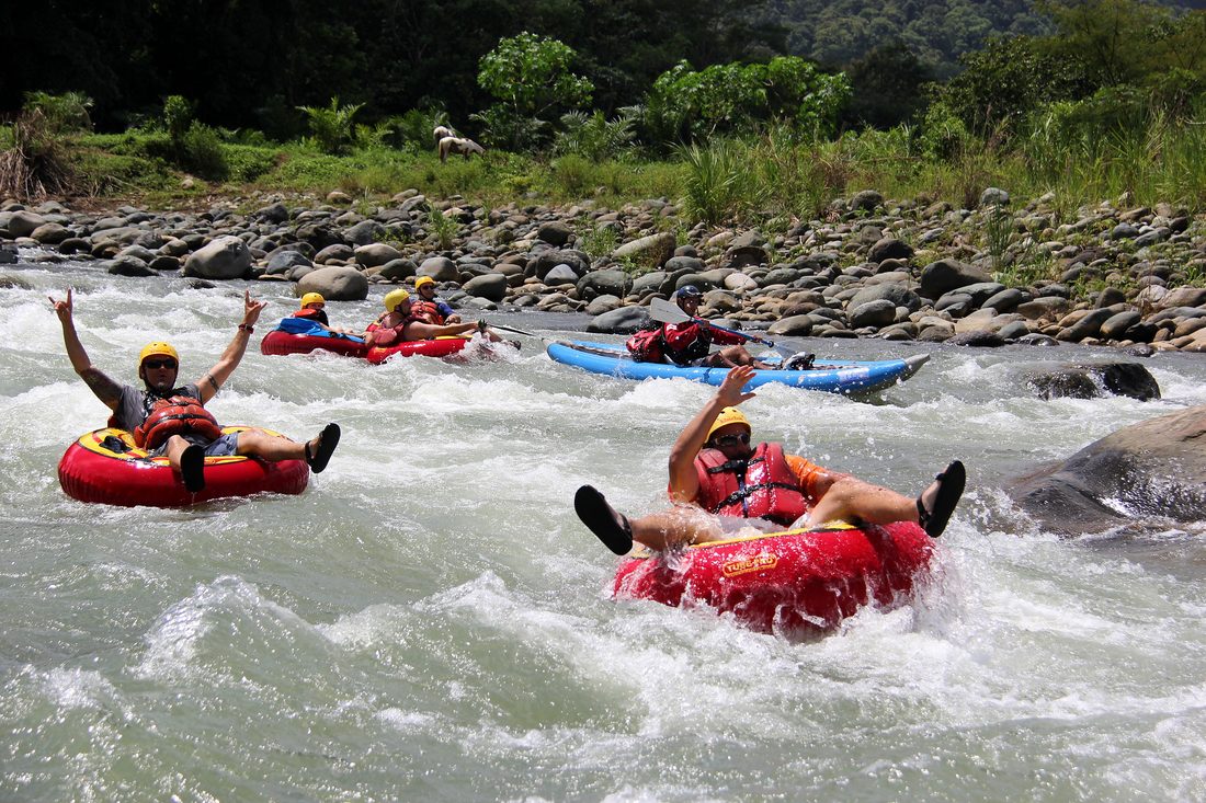 Tubers raising their arms in the rapids of the Savegre